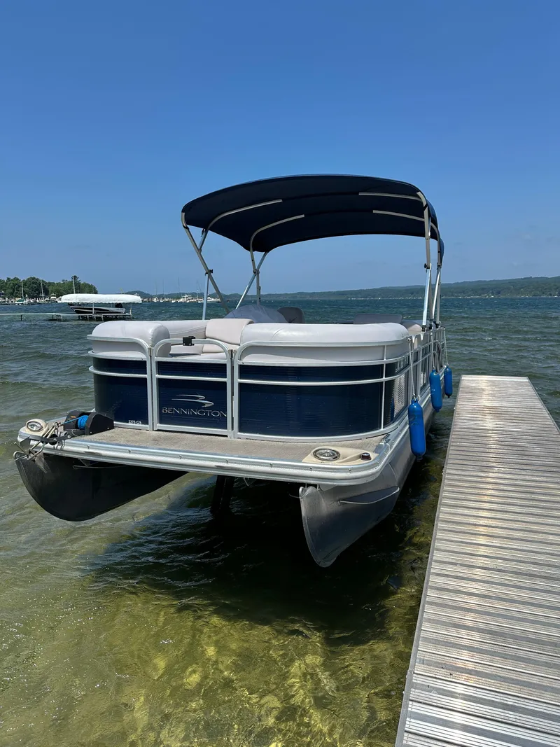 Slide: The Image of 2012 Bennington 2275 GS pontoon boat docked on a sunny lake. - 1