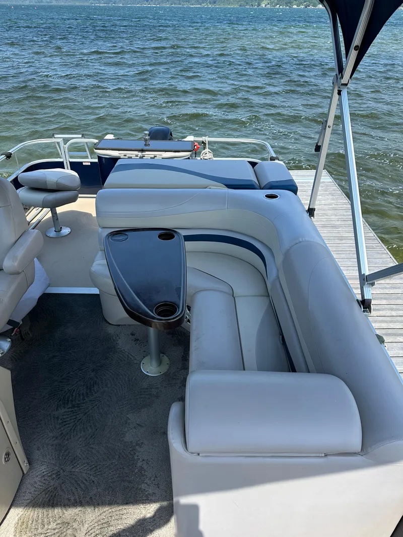 Slide: The Image of 2012 Bennington 2275 GS pontoon boat with spacious seating and table, docked by the water. - 10