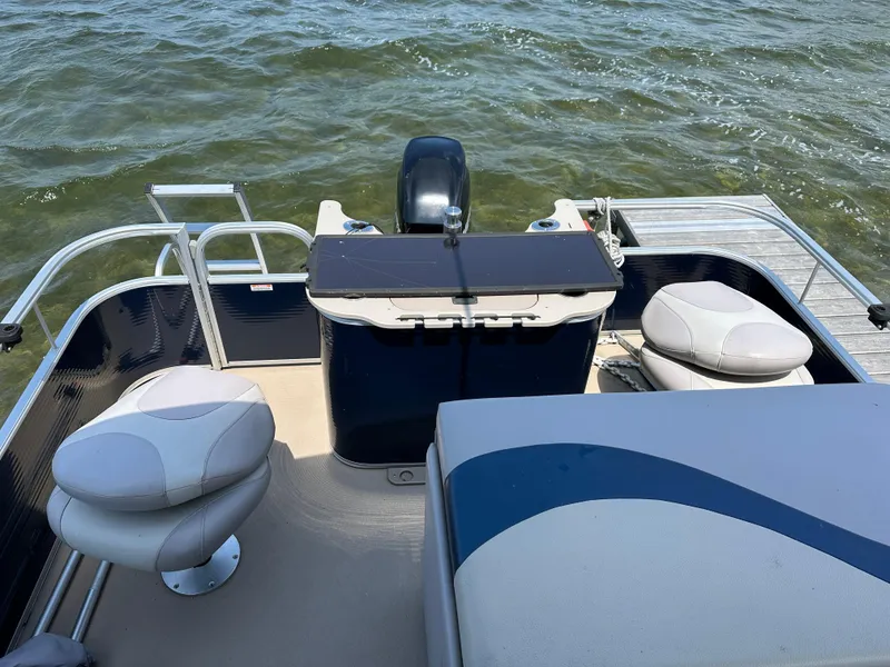 Slide: The Image of 2012 Bennington 2275 GS pontoon boat interior with seating, motor, and water view. - 12