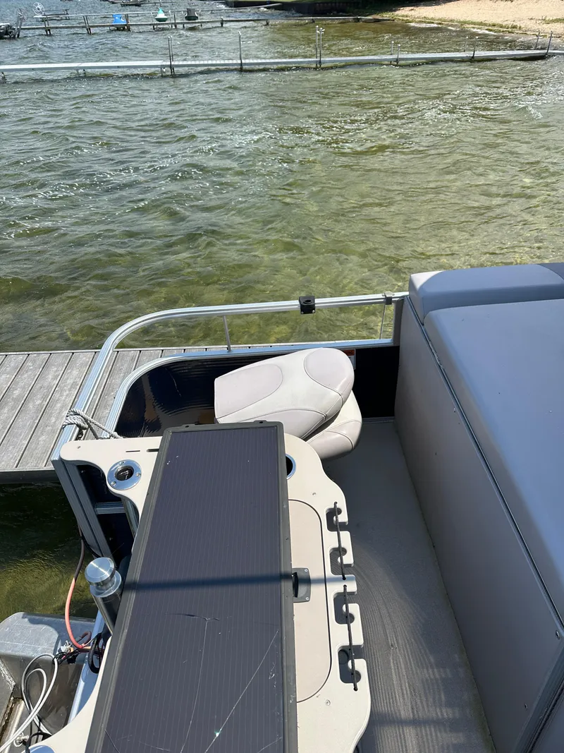 Slide: The Image of 2012 Bennington 2275 GS pontoon boat interior with seating and solar panel, docked by the water. - 13