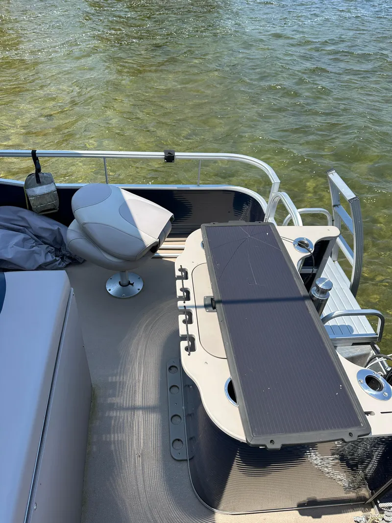 Slide: The Image of 2012 Bennington 2275 GS pontoon boat interior with seating and table on clear water. - 14