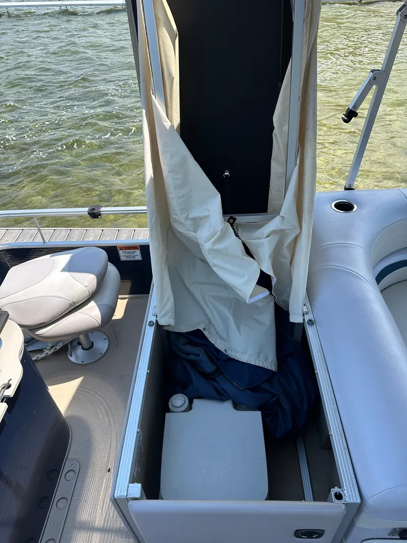 Slide: The Image of 2012 Bennington 2275 GS boat with open storage compartment and seating, near water. - 15