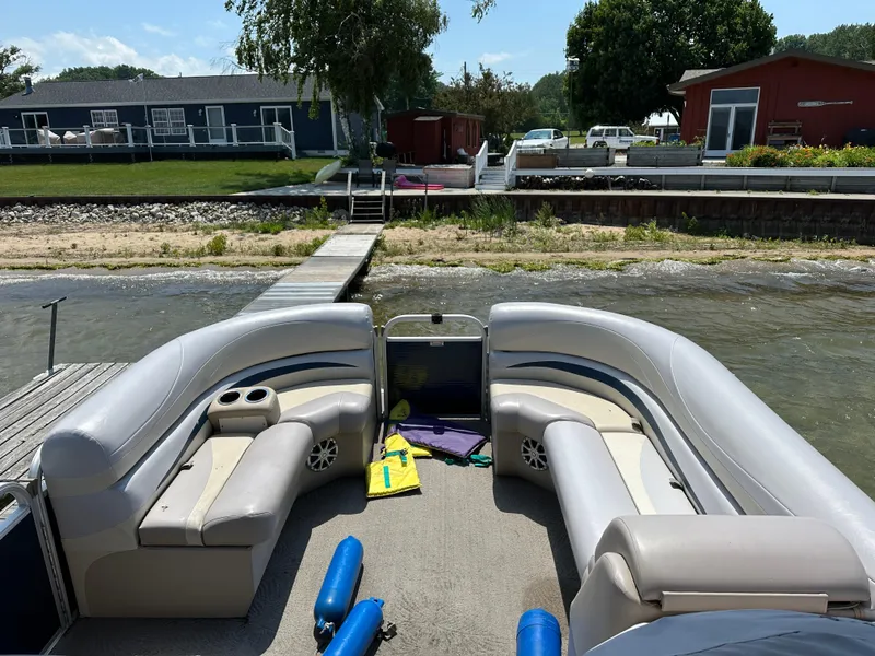 Slide: The Image of 2012 Bennington 2275 GS pontoon boat docked by a lakeside with residential backdrop. - 17
