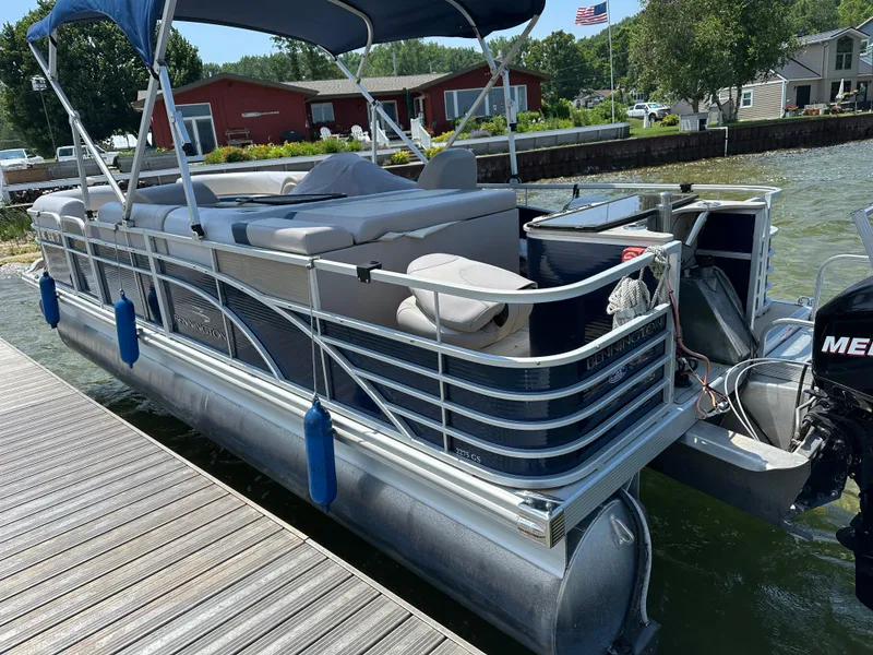Slide: The Image of 2012 Bennington 2275 GS pontoon boat docked by a lakeside with canopy and seating. - 3