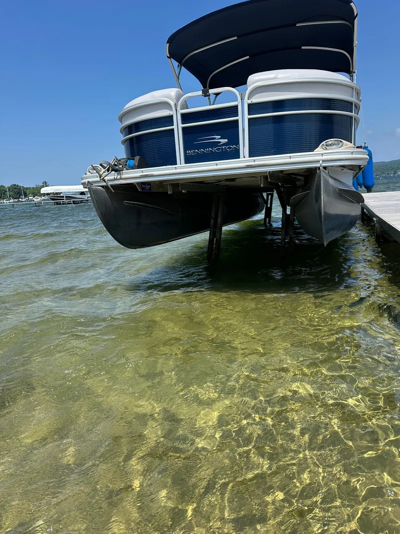 Slide: The Image of 2012 Bennington 2275 GS pontoon boat docked on clear, shallow water under a blue sky. - 6