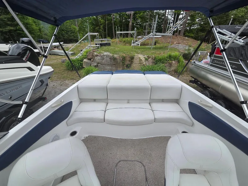 Slide: The Image of 2013 Rinker 186 Captiva boat interior with white seating and canopy, parked outdoors. - 6