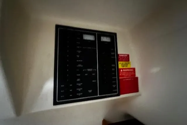 Slide: The Image of Electrical panel on a 1999 Mainship Pilot 30 Softtop Cruiser with warning labels. - 13