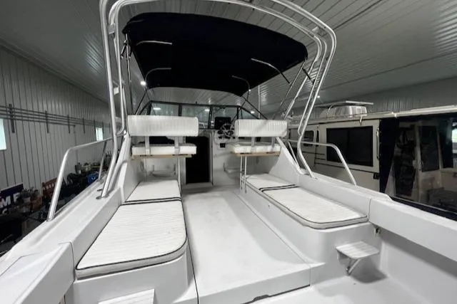 Slide: The Image of 1999 Mainship Pilot 30 Softtop Cruiser with seating and canopy in a storage facility. - 20