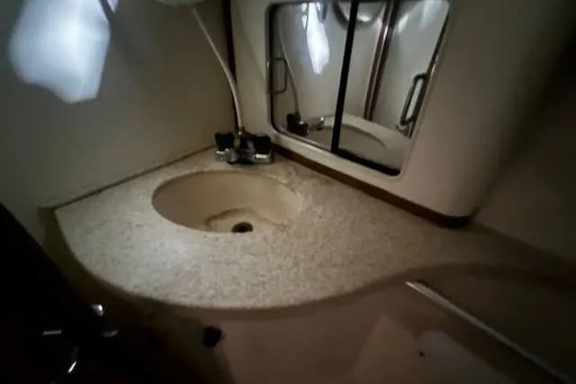 Slide: The Image of 1999 Mainship Pilot 30 Softtop Cruiser bathroom with sink and mirror. - 6