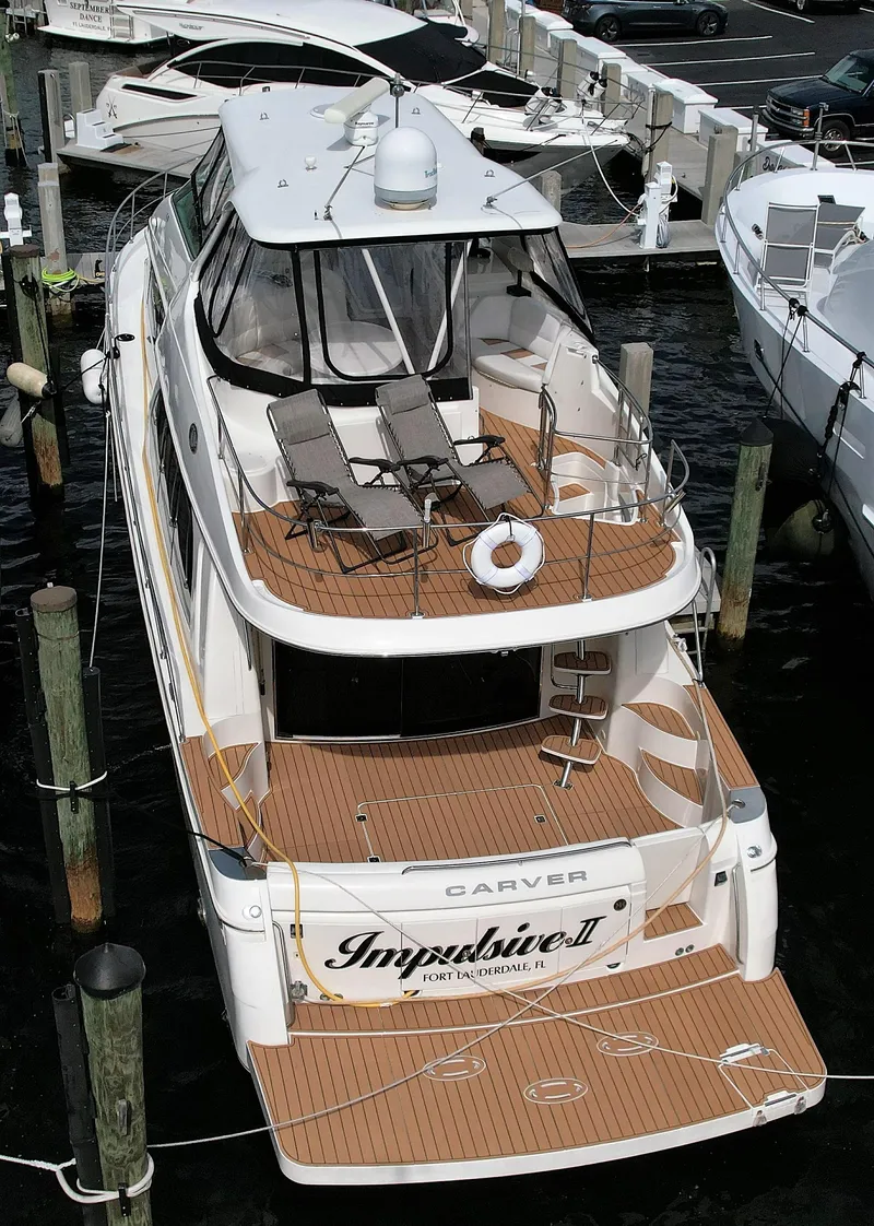Slide: The Image of 2006 Carver 56 Voyager yacht docked at marina, featuring spacious deck and sun loungers. - 2