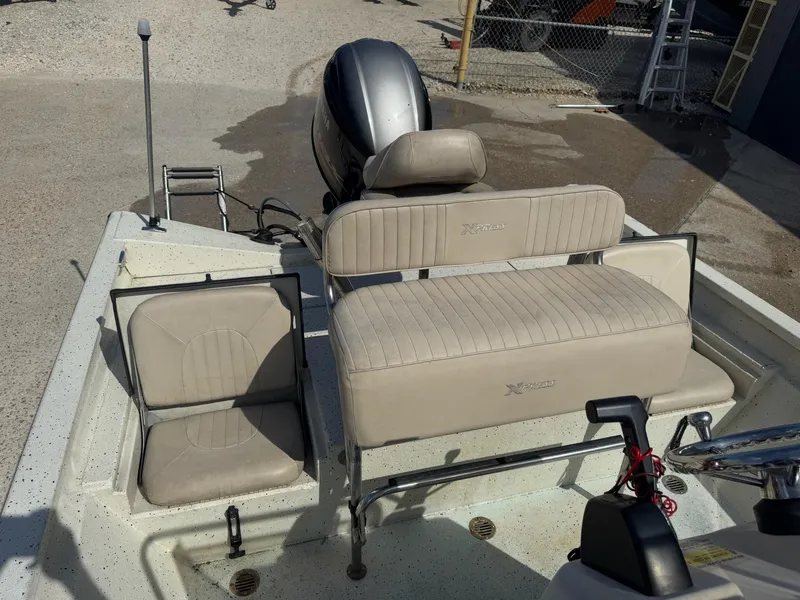 Slide: The Image of 2017 Xpress H20B boat interior with seating and motor, parked on concrete. - 14