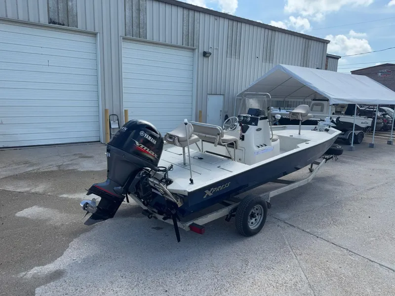 Slide: The Image of 2017 Xpress H20B boat with Yamaha outboard motor, parked outside a warehouse. - 6