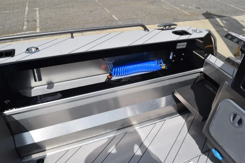 Slide: The Image of Stabicraft 2050 Treker Sportfish 2026 deck wash area with blue hose and storage compartment. - 17