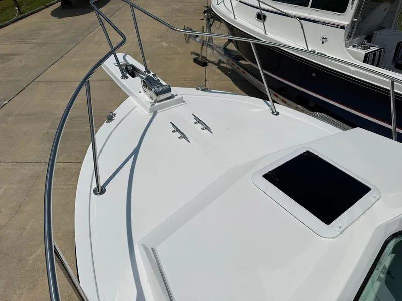 Slide: The Image of 2026 Steiger Craft 255 Miami boat deck with railing and hatch, docked beside another vessel. - 15