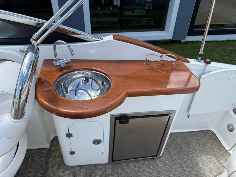 Slide: The Image of 2008 Doral 265 Elite Bowrider interior with wooden countertop, sink, and mini fridge. - 13