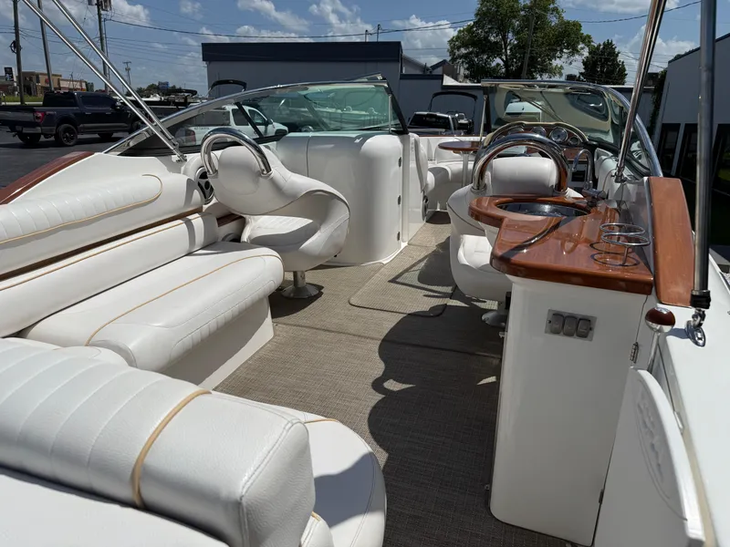 Slide: The Image of 2008 Doral 265 Elite Bowrider interior with white seating and wooden accents under sunny skies. - 15