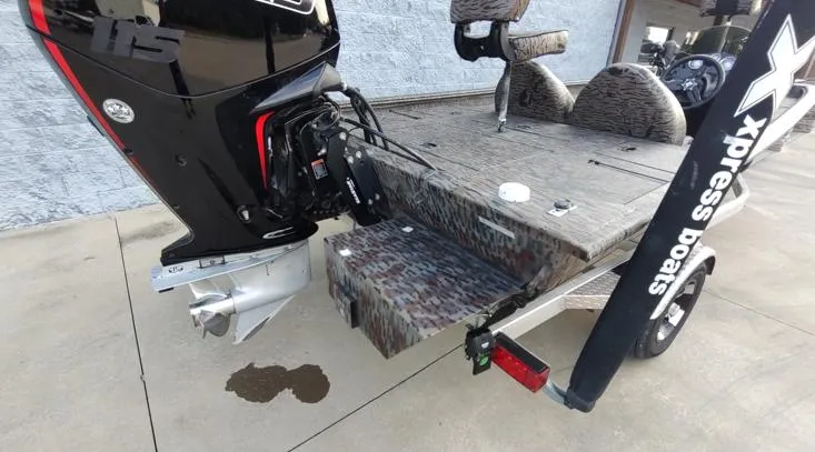 Slide: The Image of 2023 Xpress XP180 boat with powerful outboard motor and camo deck, parked on concrete. - 10