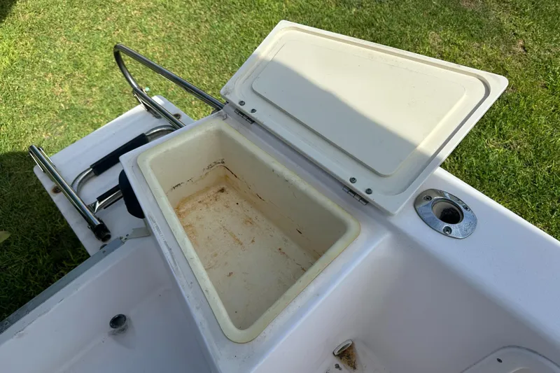 Slide: The Image of Open storage compartment on a 1996 Grady-White Spirit 175 boat, with grass in the background. - 24