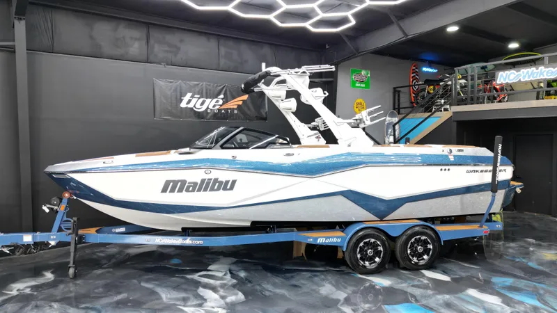 Slide: The Image of 2022 Malibu Wakesetter 25 LSV boat on trailer in showroom with modern lighting. - 1