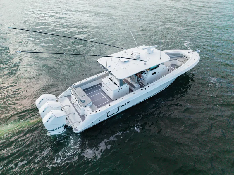 Slide: The Image of 2023 HCB 42 Lujo boat cruising on open water, featuring triple outboard engines. - 17