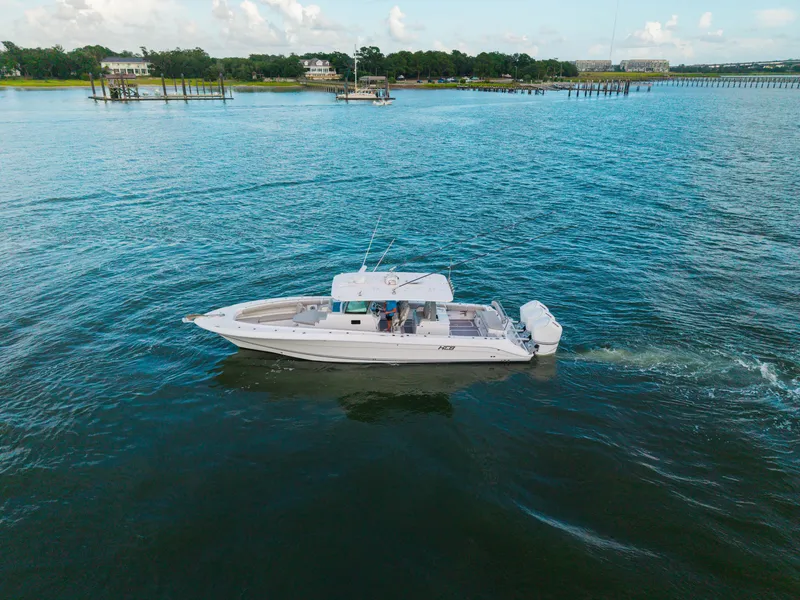 Slide: The Image of 2023 HCB 42 Lujo boat cruising on a calm blue lake with scenic shoreline. - 5