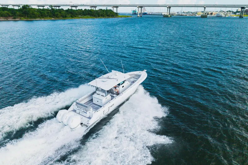 Slide: The Image of 2023 HCB 42 Lujo boat cruising on open water near a bridge. - 9