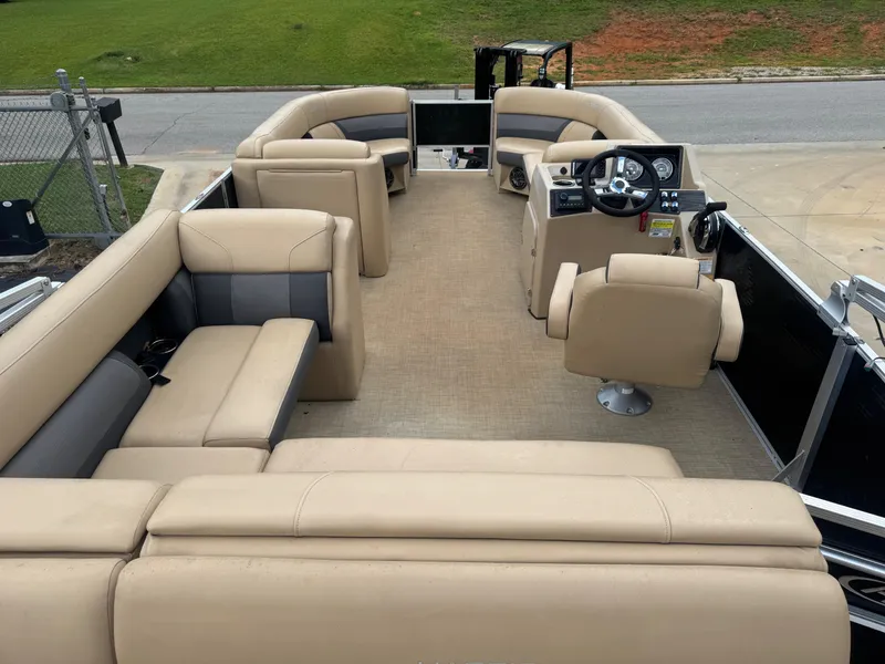 Slide: The Image of 2022 Harris Cruiser 230 pontoon boat interior with beige seating and steering console. - 2