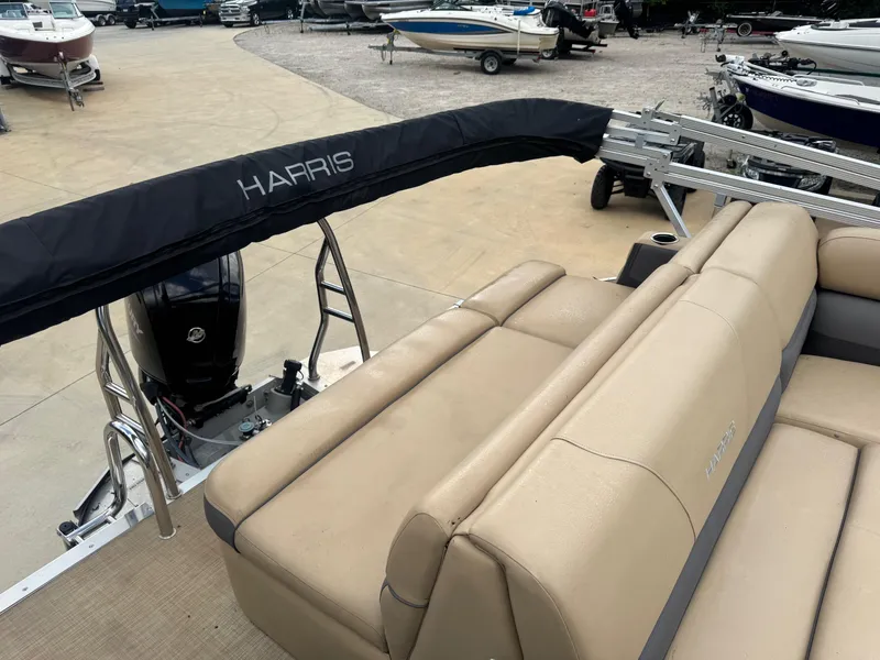 Slide: The Image of 2022 Harris Cruiser 230 pontoon boat with beige seating and covered engine, docked at a marina. - 4