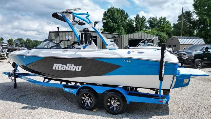 Slide: The Image of 2025 Malibu Wakesetter 23 LSV boat on trailer, blue and white design, parked outdoors. - 15