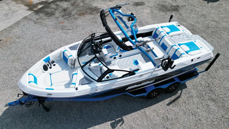 Slide: The Image of 2025 Malibu Wakesetter 23 LSV boat with blue and white interior, parked on gravel. - 17