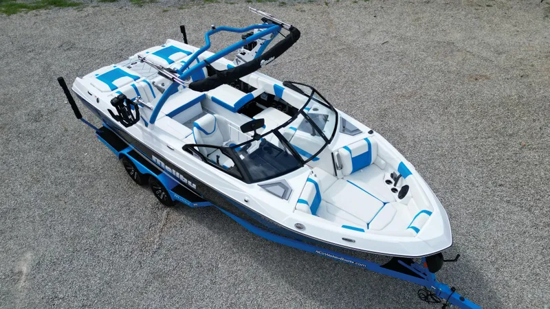 Slide: The Image of 2025 Malibu Wakesetter 23 LSV boat with blue and white interior, parked on gravel. - 4