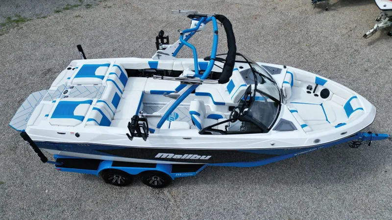 Slide: The Image of 2025 Malibu Wakesetter 23 LSV boat with blue and white interior, parked on gravel. - 5