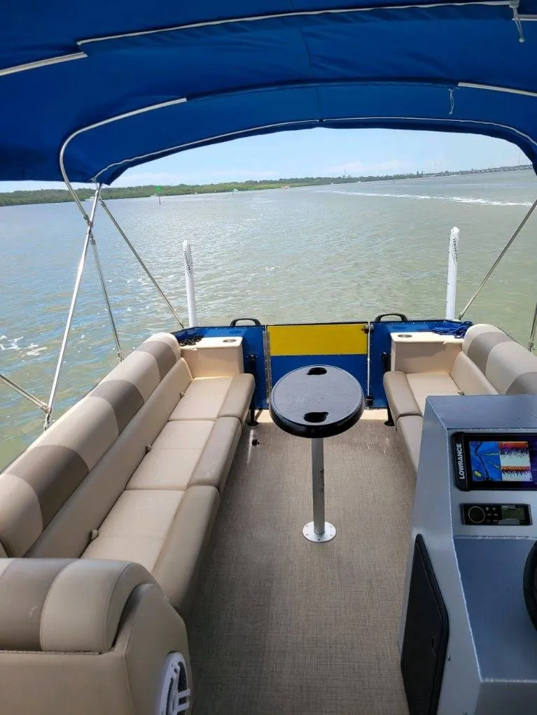 Slide: The Image of 2021 Bahama 240 Tritoon Coral Reef boat on trailer under clear blue sky. - 2