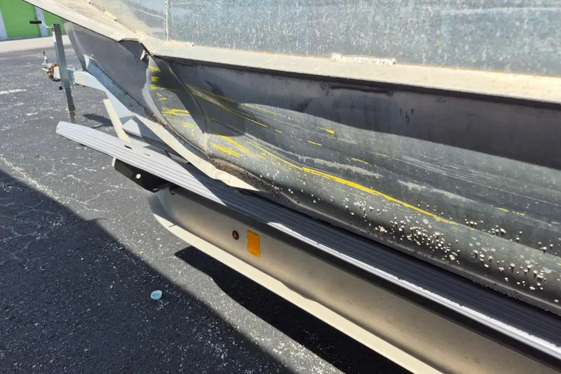 Slide: The Image of 2021 Bahama 240 Tritoon Coral Reef boat with seating and canopy, parked near RVs. - 21