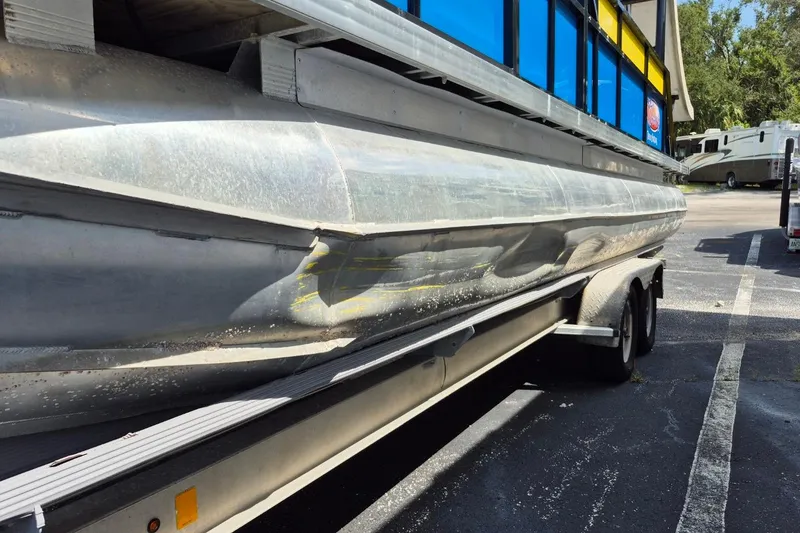 Slide: The Image of 2021 Bahama 240 Tritoon Coral Reef boat on trailer, showing hull damage. - 23