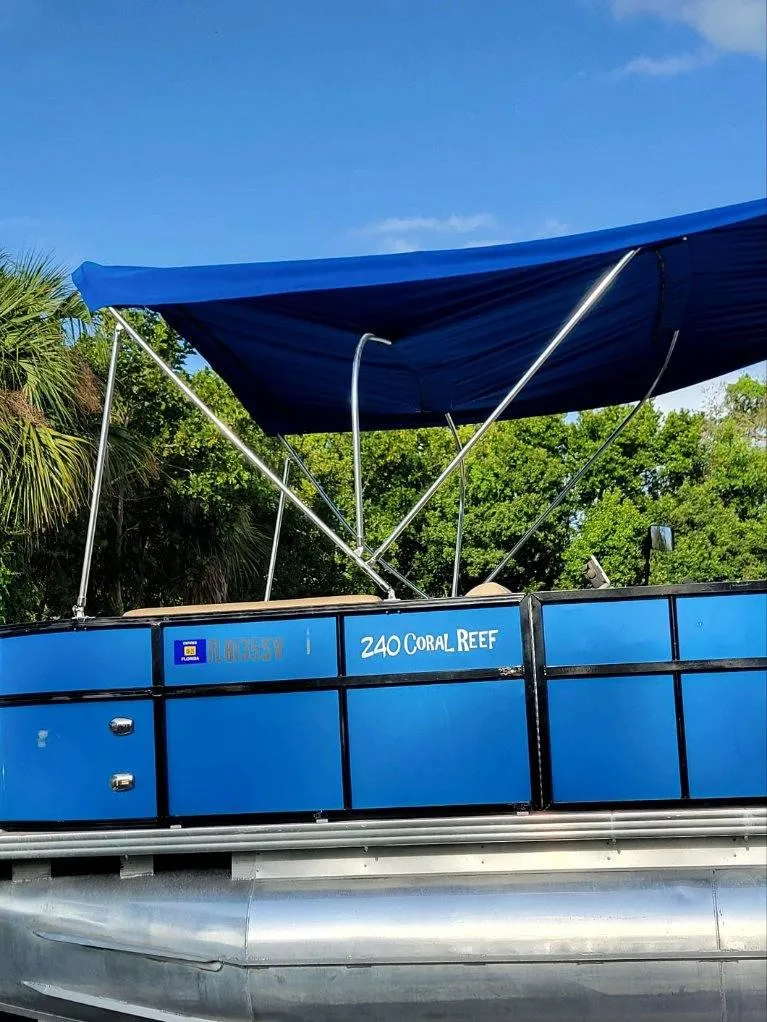 Slide: The Image of 2021 Bahama 240 Tritoon Coral Reef boats docked at marina with parked car nearby. - 9