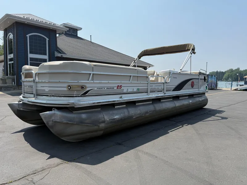 The Image of 2000 Sun Tracker PARTY BARGE 25 pontoon boat parked near a waterfront building. - 0