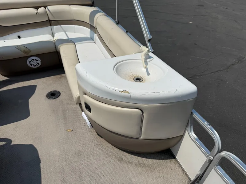 Slide: The Image of Sun Tracker PARTY BARGE 25 interior with seating and a small sink, showing wear and cracks. - 11