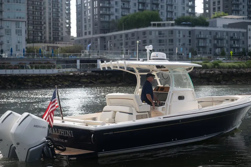 Slide: The Image of 2019 Hunt Yachts 32 Center Console boat on urban waterway, American flag displayed. - 10