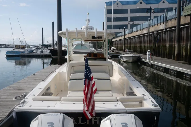 Slide: The Image of 2019 Hunt Yachts 32 Center Console docked, featuring American flag and twin Mercury engines. - 15