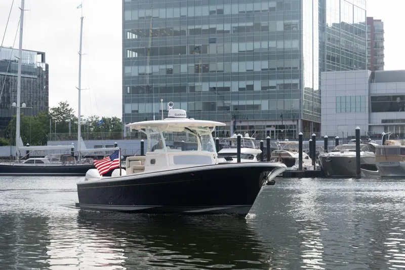 Slide: The Image of 2019 Hunt Yachts 32 Center Console in marina, cityscape background, American flag displayed. - 2