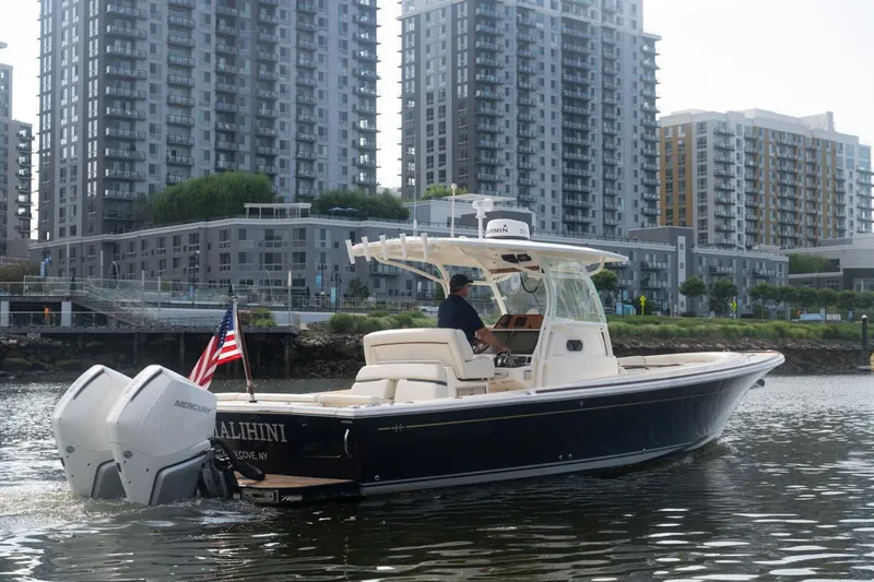 Slide: The Image of 2019 Hunt Yachts 32 Center Console cruising near urban waterfront with modern buildings. - 3