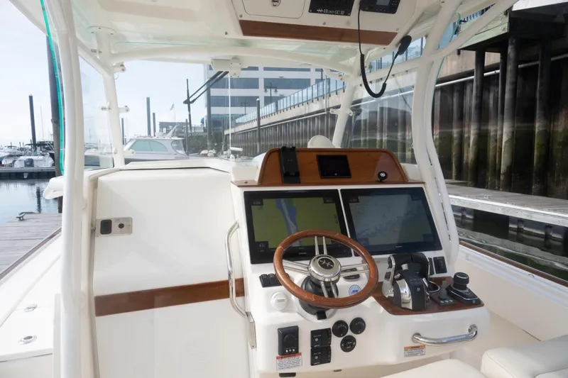 Slide: The Image of 2019 Hunt Yachts 32 Center Console helm with dual screens and controls at marina. - 40