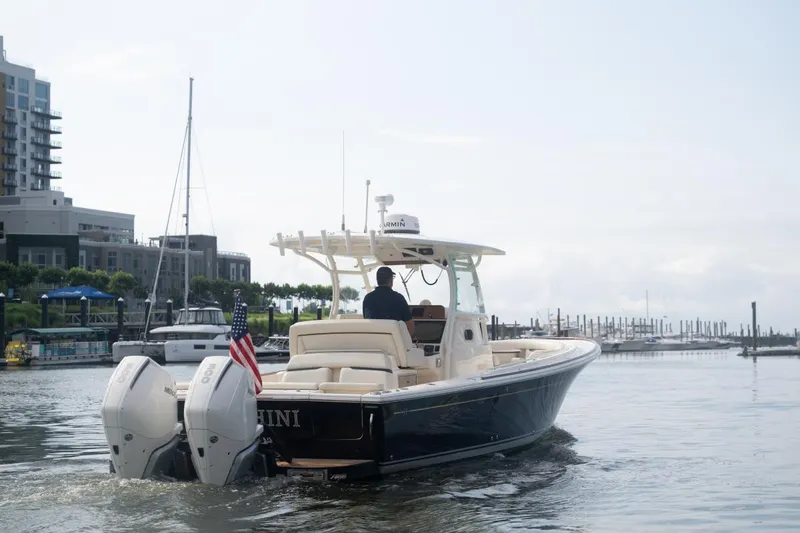 Slide: The Image of 2019 Hunt Yachts 32 Center Console cruising in a marina, featuring twin outboard engines. - 5