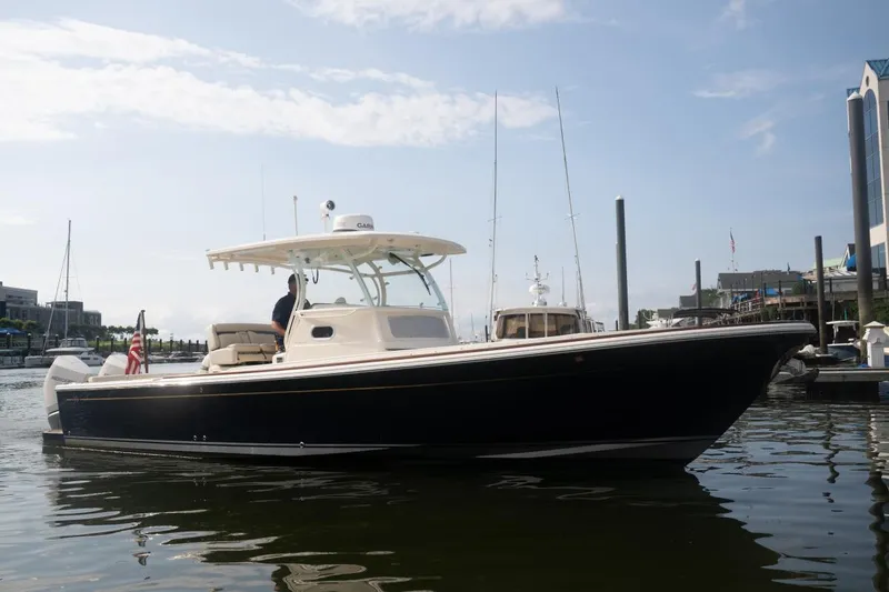 Slide: The Image of 2019 Hunt Yachts 32 Center Console boat docked in a marina under a clear sky. - 7