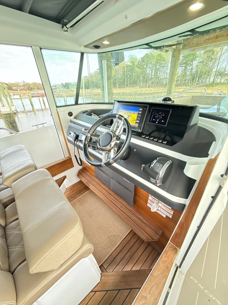 Slide: The Image of 2019 Axopar 28 CABIN interior with modern helm, steering wheel, and navigation screens. - 16