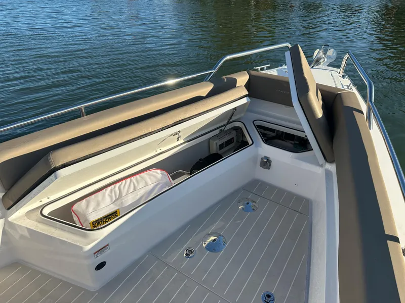 Slide: The Image of 2019 Axopar 28 CABIN boat interior with seating and storage, on calm water. - 21