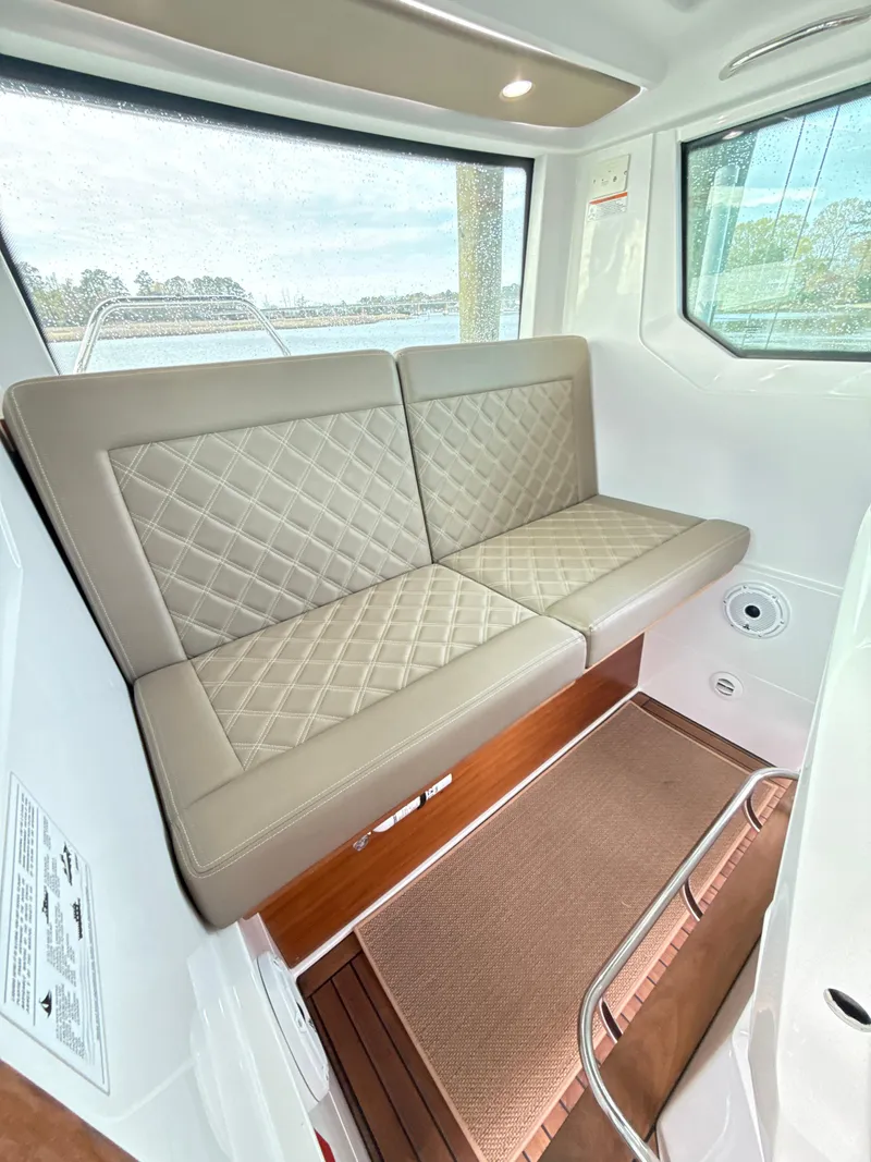 Slide: The Image of Interior of 2019 Axopar 28 CABIN with beige quilted seating and wooden flooring. - 31