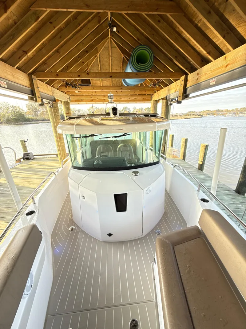 Slide: The Image of 2019 Axopar 28 CABIN boat docked under wooden shelter by the water. - 32