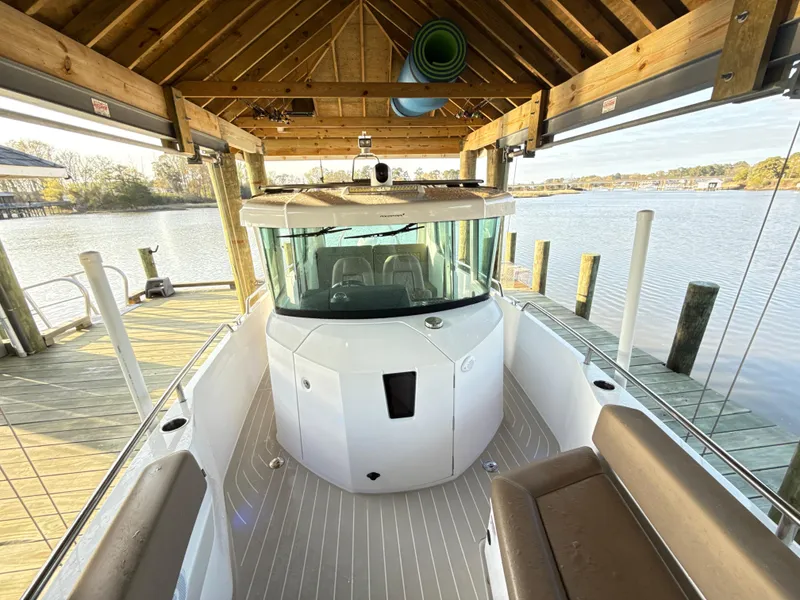 Slide: The Image of 2019 Axopar 28 CABIN boat docked under wooden shelter by the water. - 33